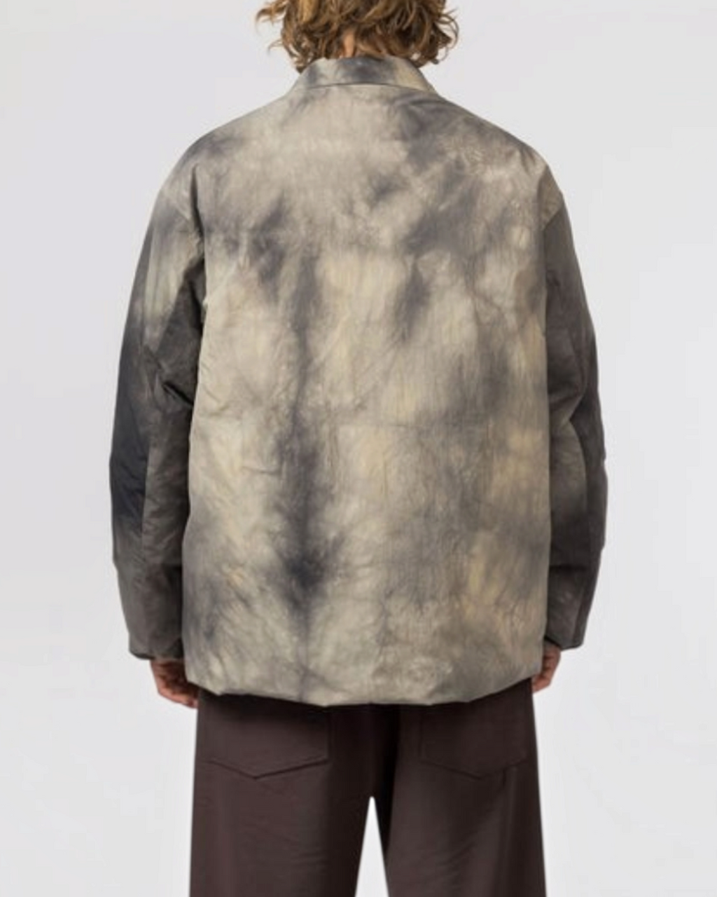 Vue arrière d'un homme portant la veste Merci Paris Snow Peak en nylon avec motif Shibori teinté couleur charbon.