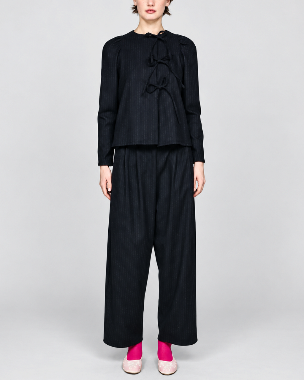 Modèle portant la chemise noire à rayures tennis ELEPH avec fermeture à nœuds et épaules froncées chez Merci Paris