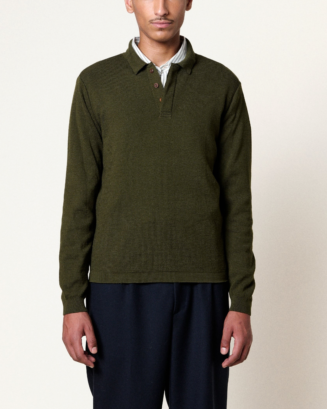 Homme portant le polo Nemesis kaki en laine mérinos de Merci Paris avec col boutonné et détails en corozo