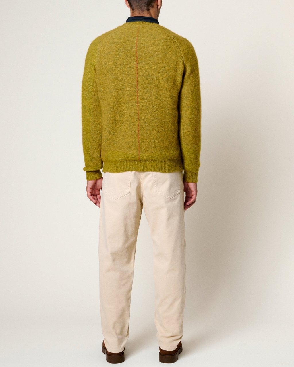 Pull Merci Paris Homecore Baby Brett en alpaga vert avec couture rouge au dos porté par un homme de dos
