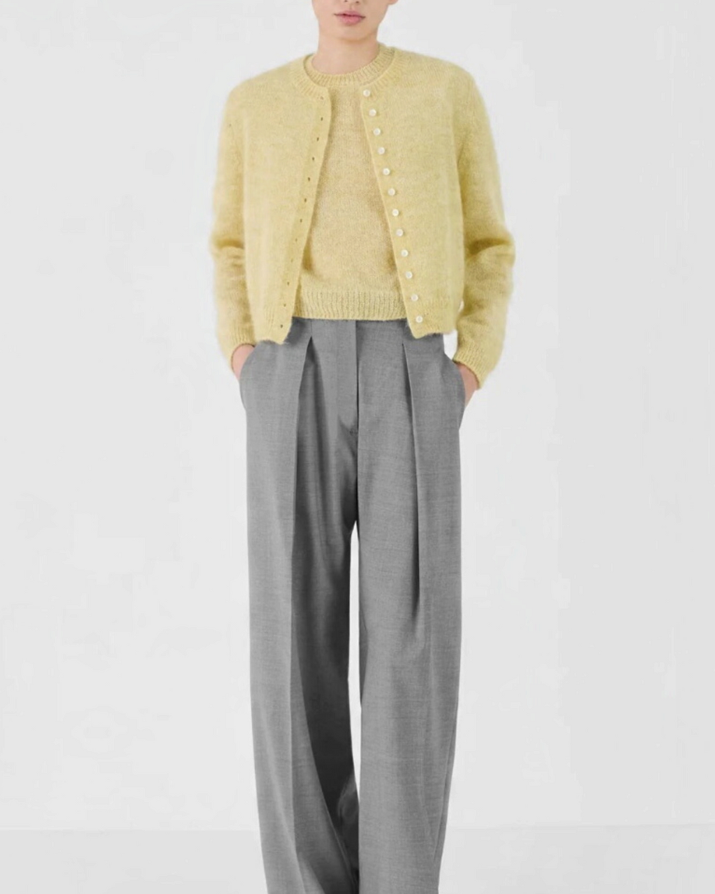 Mannequin portant le cardigan court Merci Paris Masscob en mohair jaune citron avec un pantalon gris large