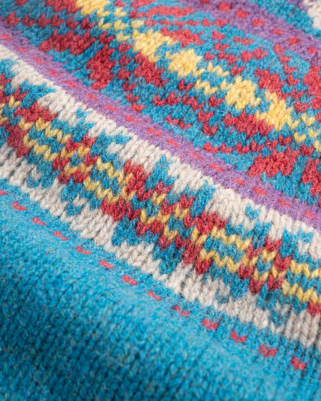 Gros plan sur le motif jacquard coloré en laine Shetland du pull Merci Paris Howlin' Living In The Light bleu