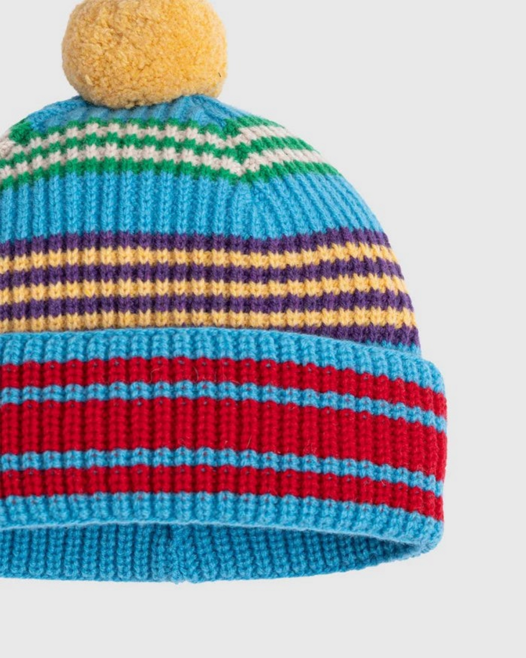 Bonnet Merci Paris Howlin' en laine d'agneau rayé bleu avec pompon jaune, tricoté en Écosse