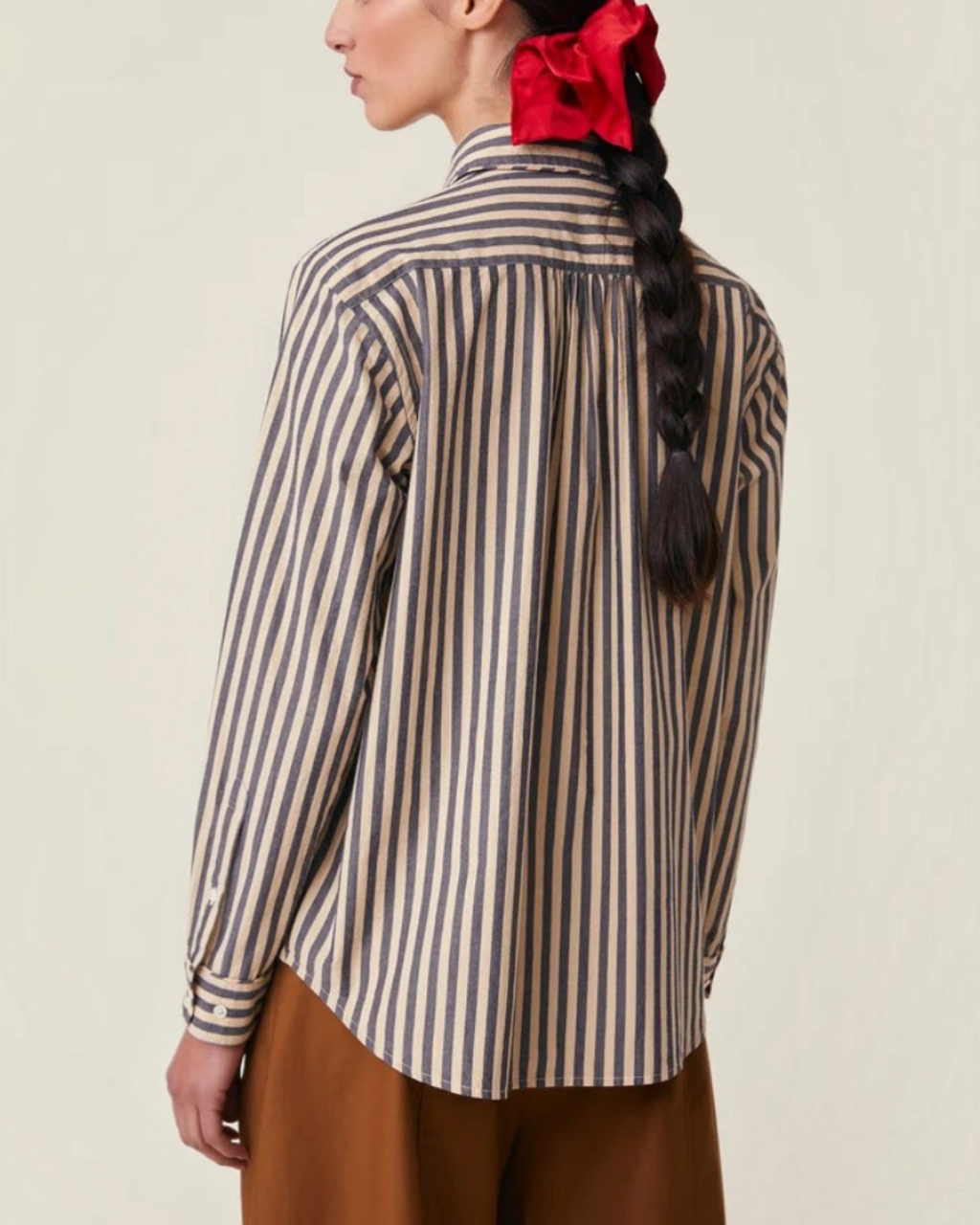 Vue de dos de la chemise Henriette Moismont à rayures bleues portée par une femme avec une tresse et un chouchou rouge