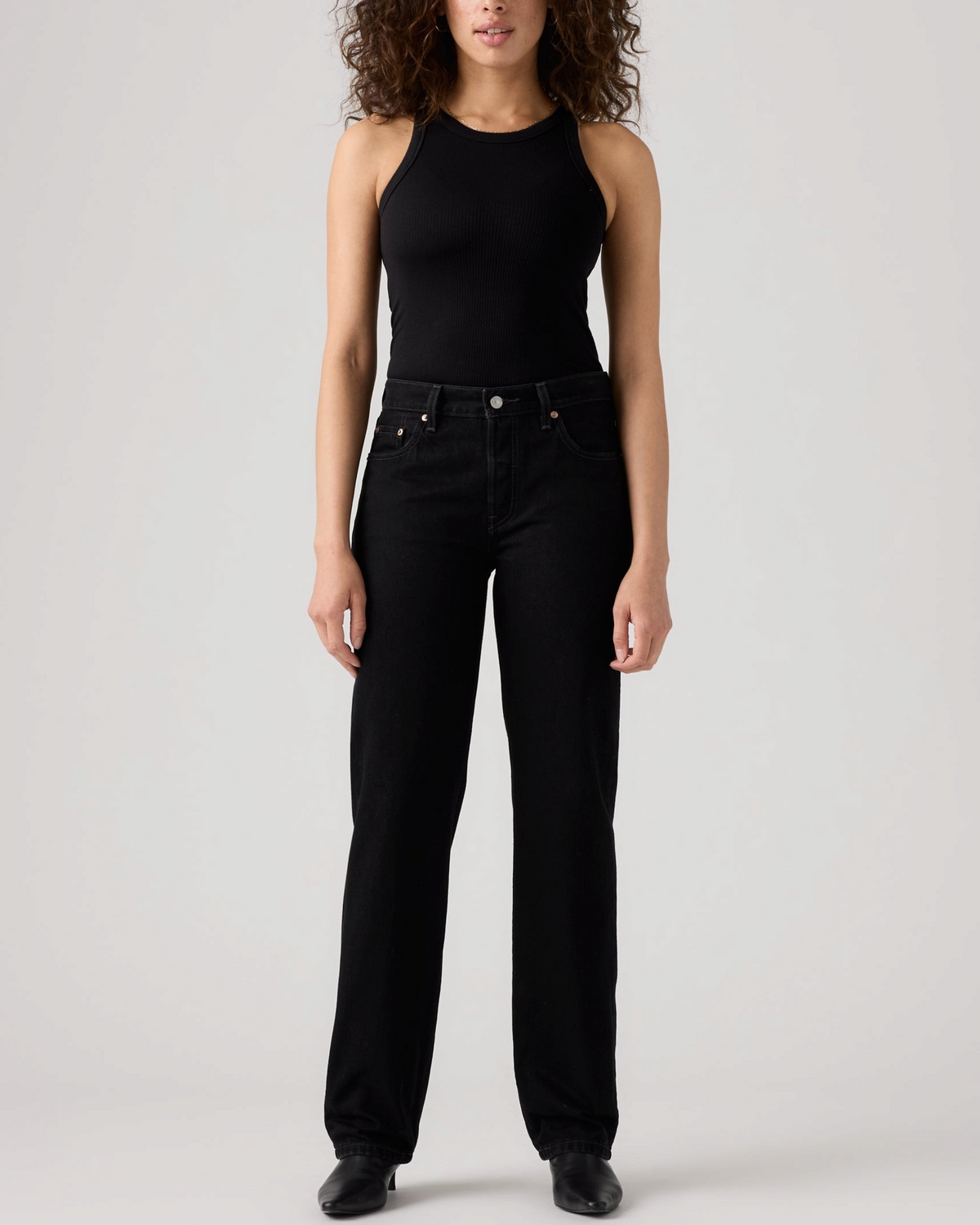 Modèle portant un jean Levi's 501 '90 noir coupe droite en coton rigide, disponible chez Merci Paris