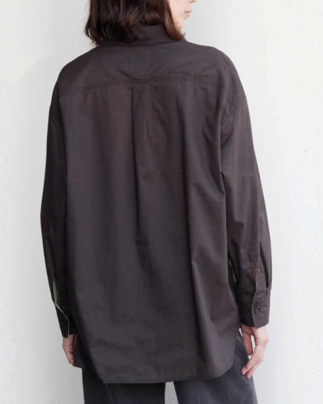 Vue arrière d'une femme portant la chemise réversible Merci Paris en coton biologique marron foncé, coupe oversize.