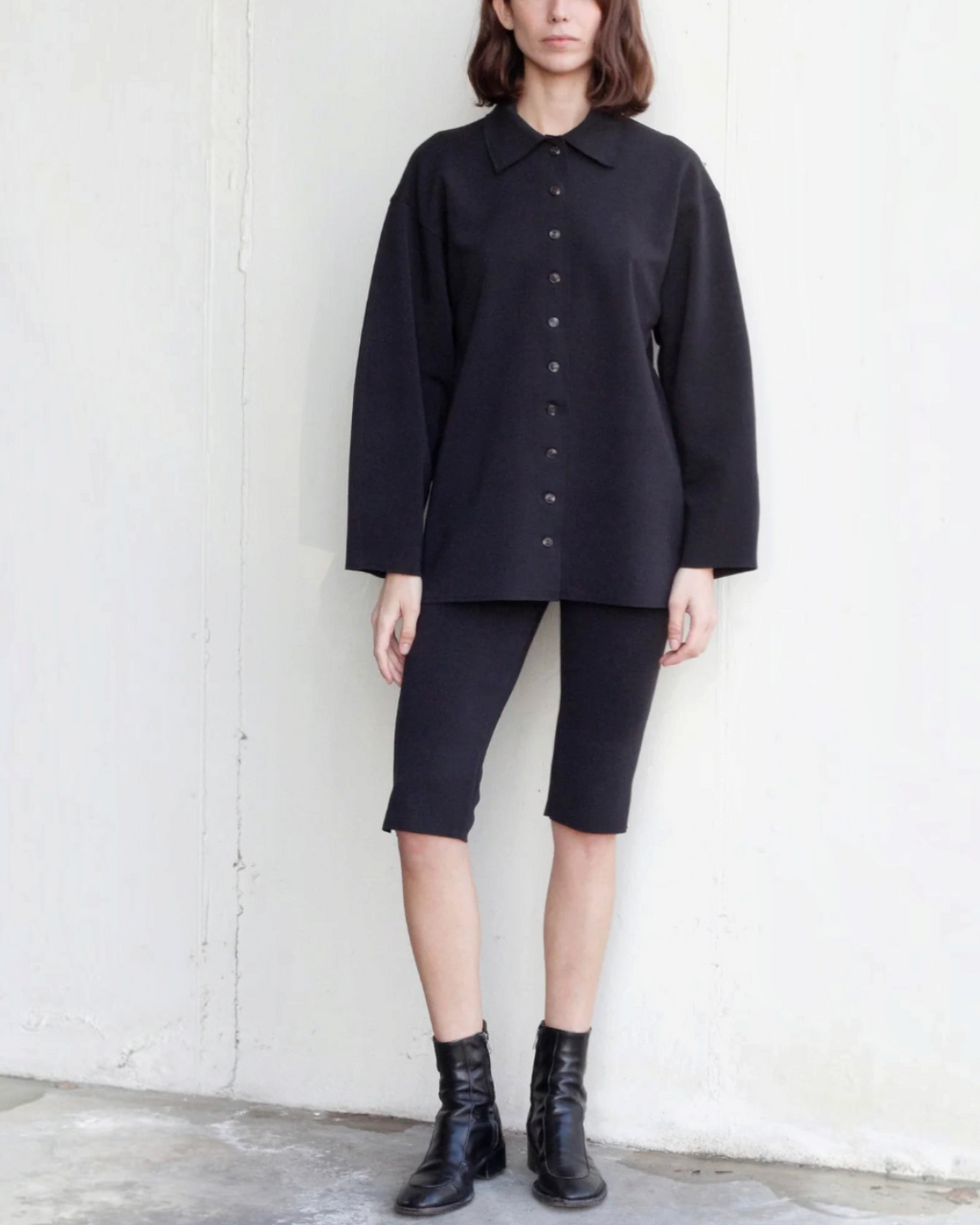 Mannequin portant le bermuda noir en maille Black to Grey de Merci Paris avec une chemise assortie et des bottines