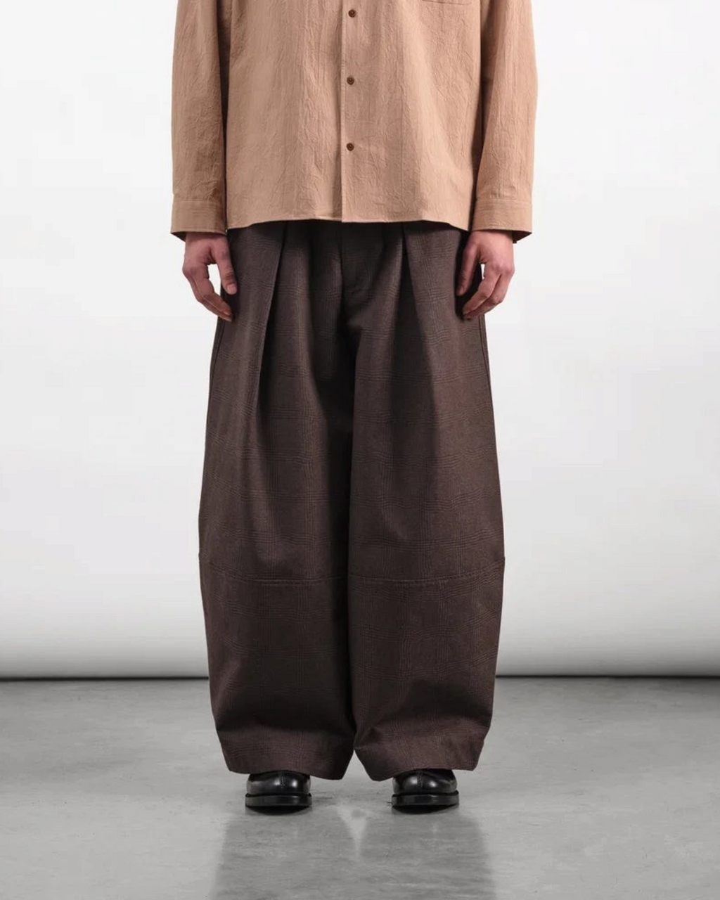 Homme portant le pantalon Deadbeat marron de Merci Paris avec une coupe large, taille haute et plis marqués