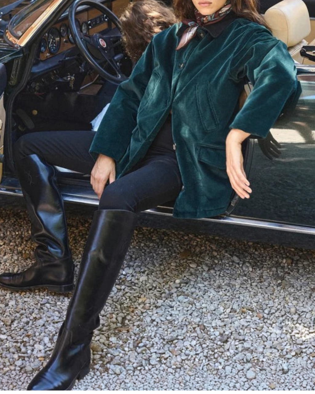 Femme portant la veste Pemberton Merci Paris en velours côtelé vert avec col en daim, assise dans une voiture décapotable