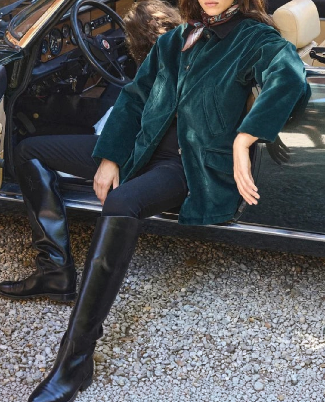 Femme portant la veste Pemberton Merci Paris en velours côtelé vert avec col en daim, assise dans une voiture décapotable