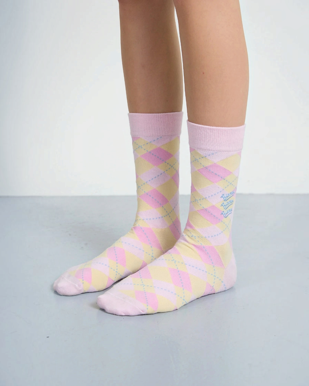 Chaussettes Merci Paris Bisous Skateboard en coton rose et jaune avec motif argyle et broderie bleue à la cheville