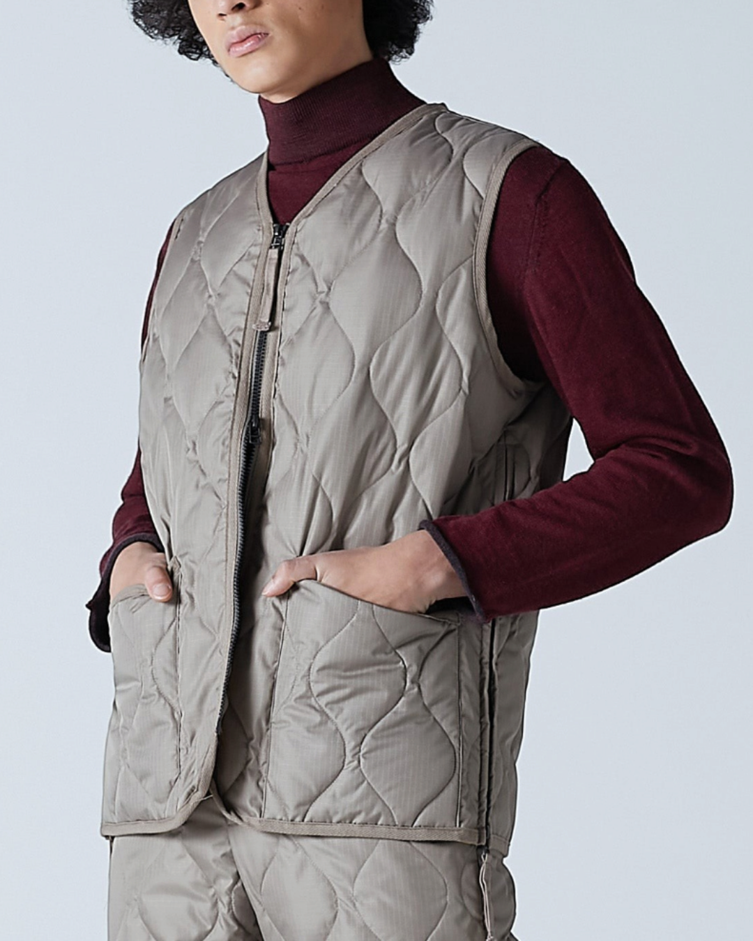 Homme portant un gilet matelassé Merci Paris Taion couleur moka avec col en V, zip et tissu ripstop