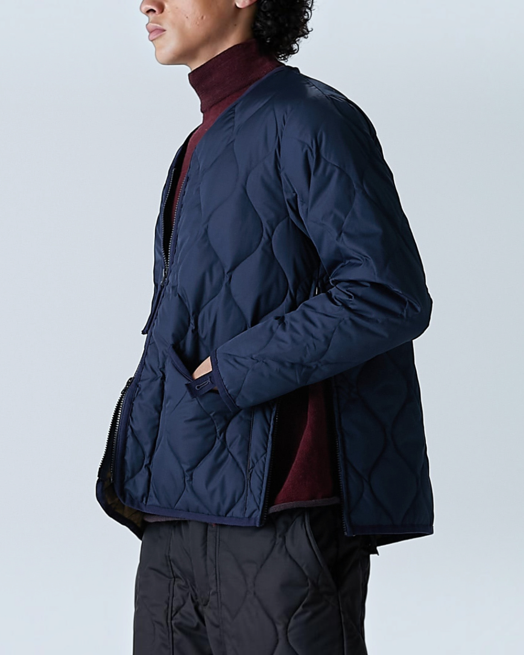 Veste matelassée bleu marine Taion Military Zip V-Neck portée par un homme, style urbain avec fentes latérales.
