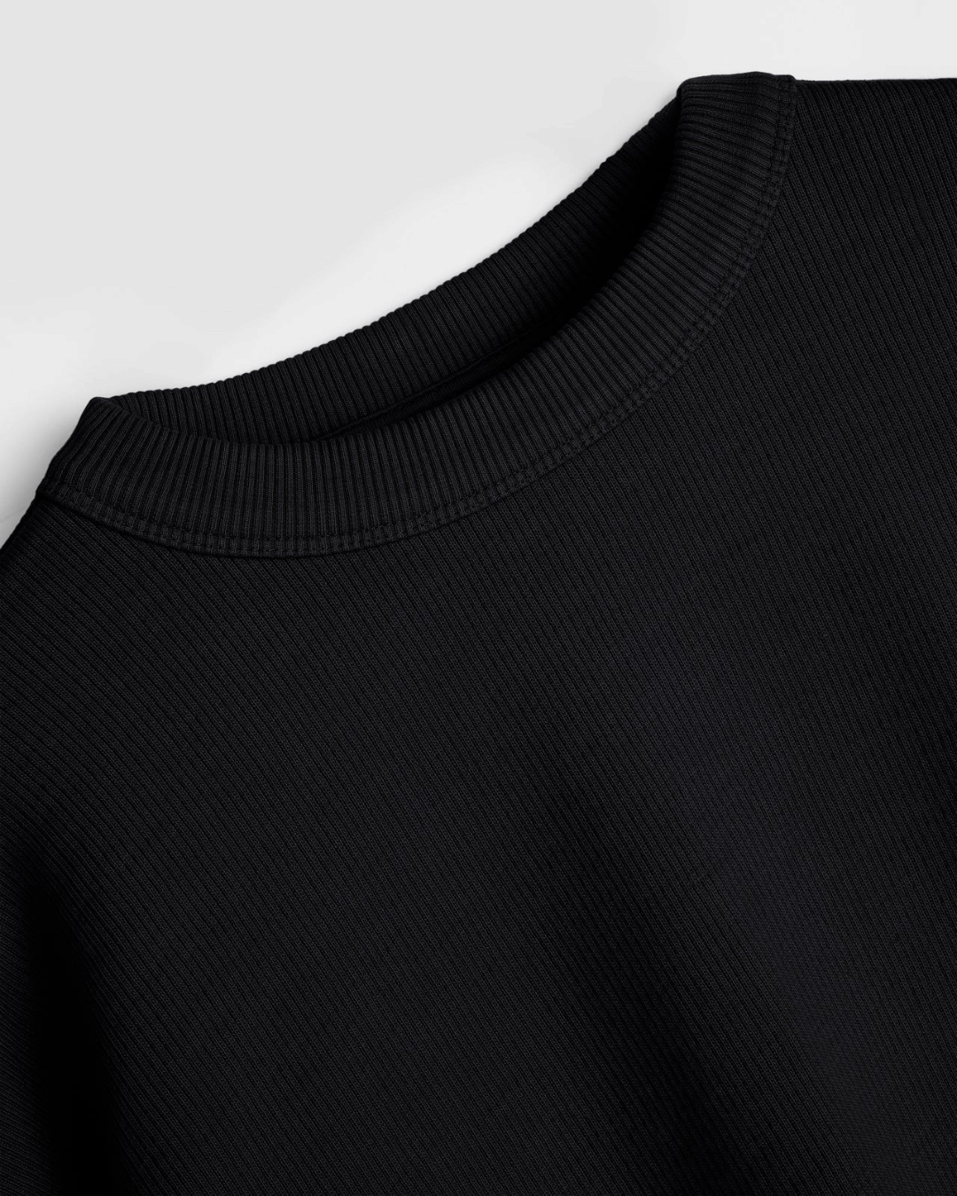 Gros plan sur le col rond côtelé du sweat-shirt noir YMC en coton bouclette épais chez Merci Paris
