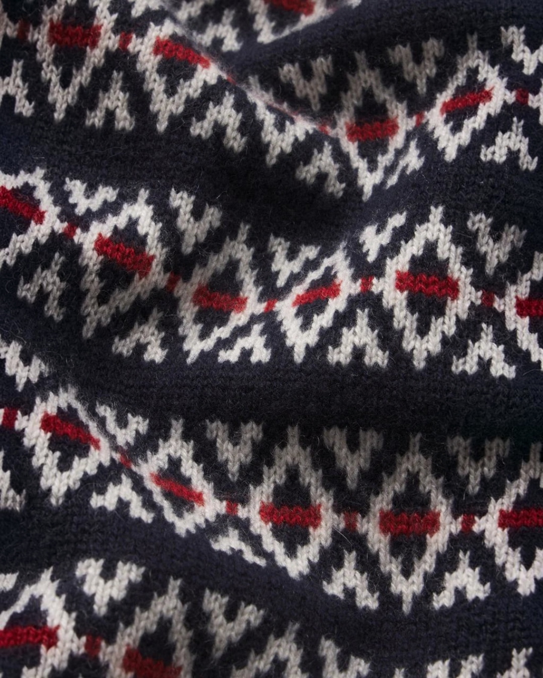 Gros plan sur le motif Fairisle bleu marine, blanc et rouge du cardigan en laine et cachemire Merci Paris par Frame