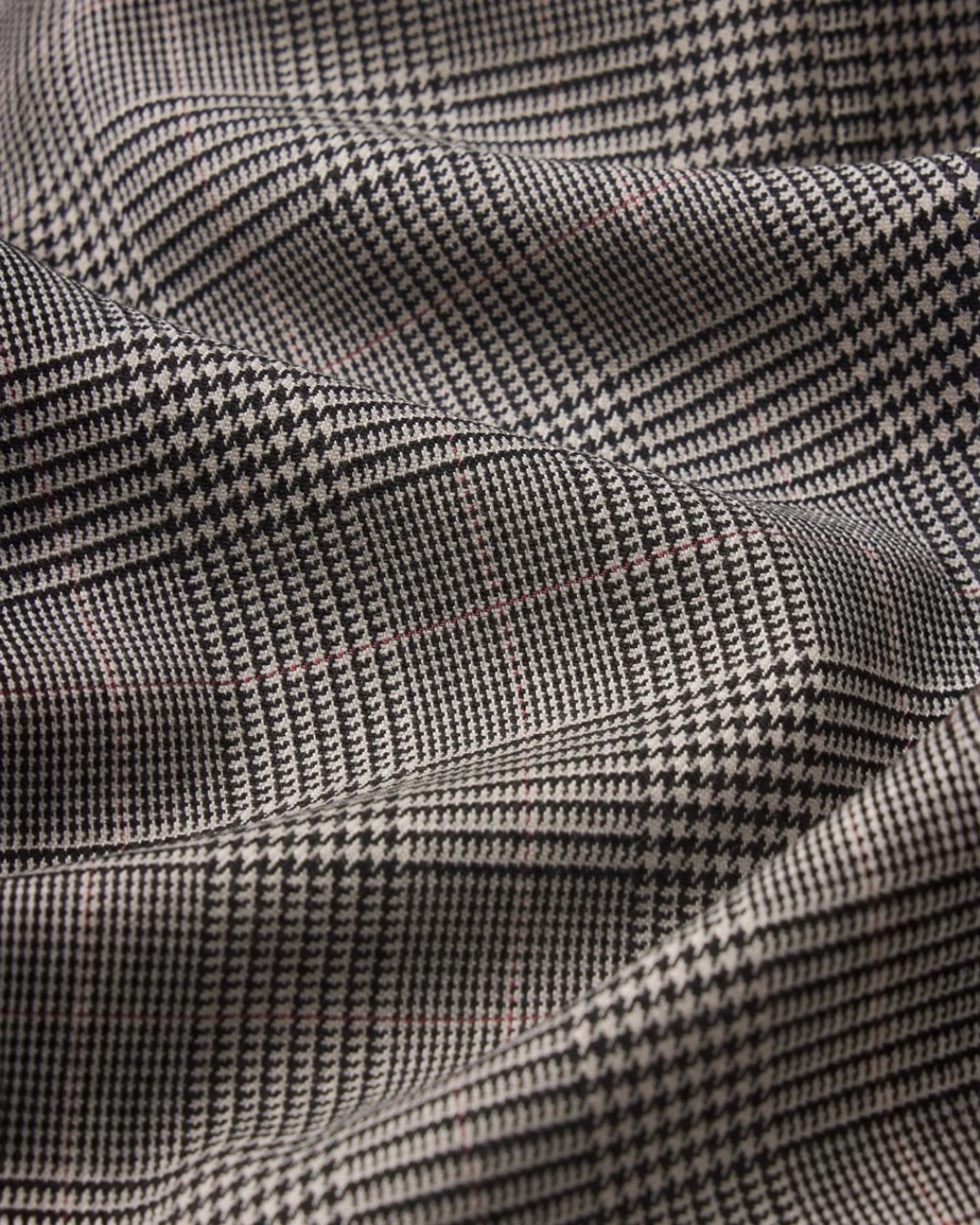 Gros plan sur le tissu en laine mélangée à motif pied-de-poule noir et blanc de la veste Merci Paris Frame