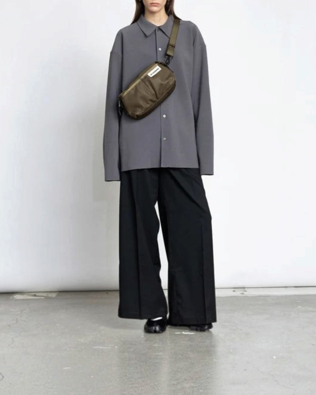 Modèle portant un sac bandoulière kaki Merci Paris en nylon recyclé au design minimaliste scandinave